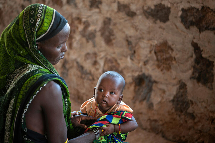 Robe Denge holds her baby as they wait outside a WFP supported nutrition clinic in the village Malabot in Marsabit County in northern Kenya. Photo: WFP/Alessandro Abbonizio